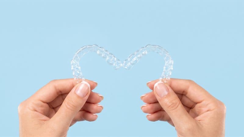 Alineador transparente de ortodoncia invisible sostenido con las manos