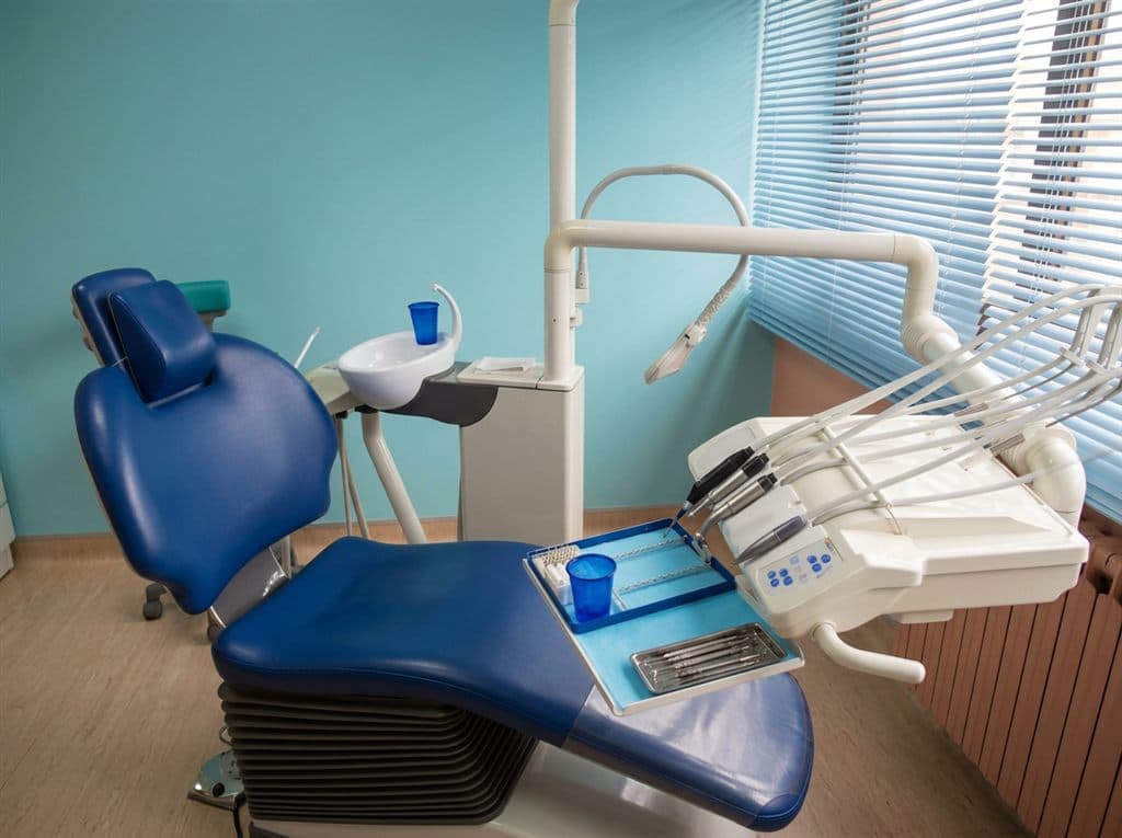 Sillón dental y unidad de tratamiento junto a la ventana en la clínica dental de Chantada